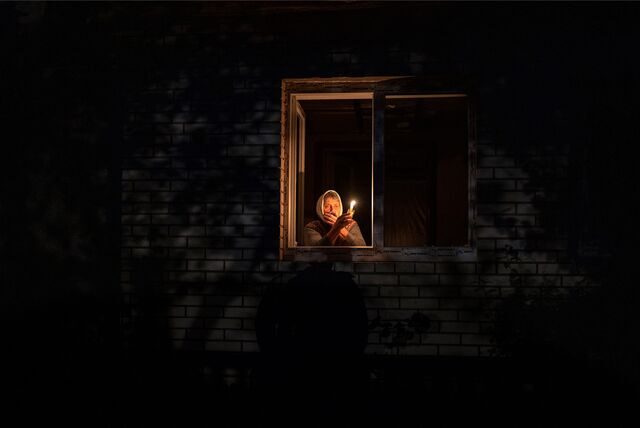 Die 70-Jährige Catherine steht während eines Stromausfalls mit einer Kerze in der Hand am Fenster.
