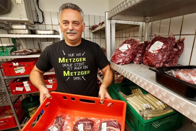 Dirk Flechsig hält eine Kiste mit verpacktem Fleisch in den Händen.