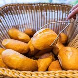 Eine Verkäuferin nimmt ein Brötchen mit einer Zange aus einem Brötchenkorb.