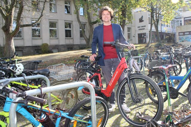 Unnas Klimaschutzmanager Thomas Heer zeigt Fahrradständer an einem Schulgebäude, wo vorher Lehrerparkplätze waren.