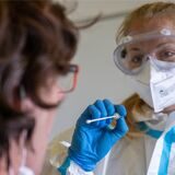 Eine Frau in Schutzkleidung führt einen Corona-Test durch.