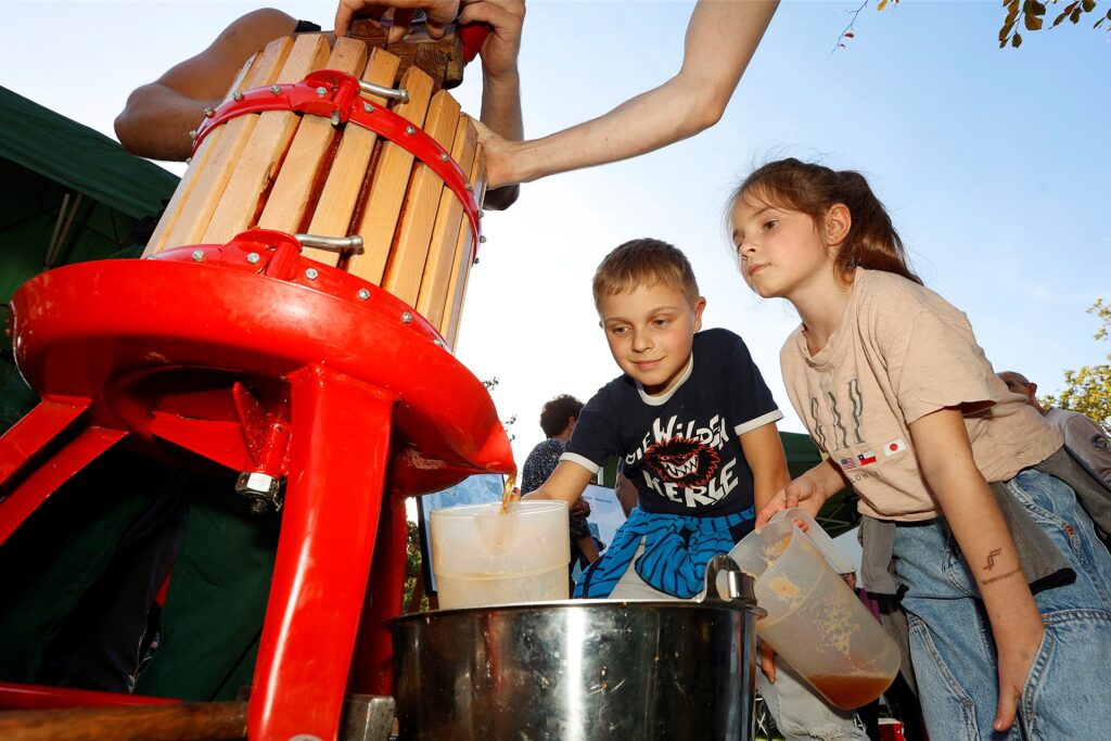 Paula (8) und ihr Bruder Emil (10) sind beim Tag des Apfels auf der Öko-Station fasziniert von der handbetriebenen Apfelpresse. Paula (8) und ihr Bruder Emil (10) sind beim Tag des Apfels auf der Öko-Station fasziniert von der handbetriebenen Apfelpresse.