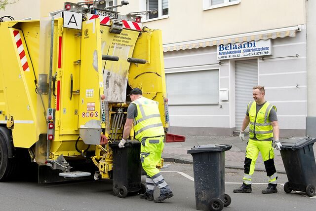 Zwei Männer bringen Mülltonnen an ein Fahrzeug der EDG.