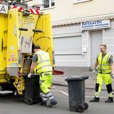 Zwei Männer bringen Mülltonnen an ein Fahrzeug der EDG.