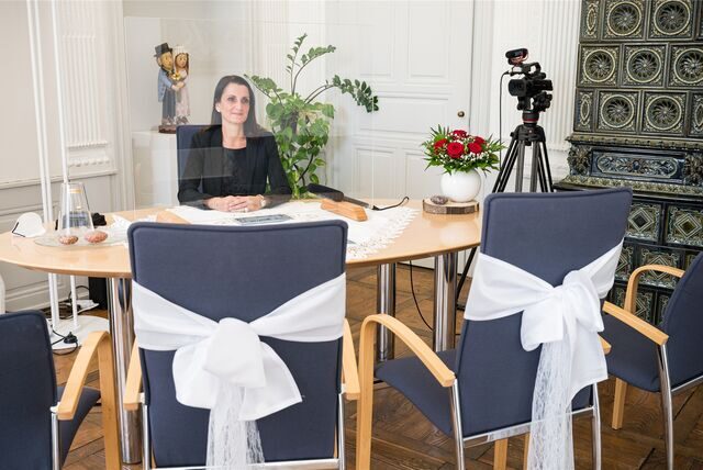 Eine Standesamtbeamtin sitzt am Trautisch. Hinter ist eine Videokamera aufgebaut.
