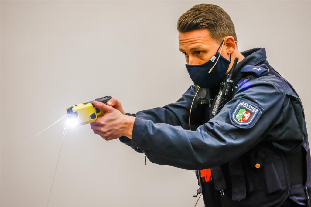 Ein Polizeibeamter führt den Einsatz einer Elektroimpulswaffe, auch Taser genannt, vor. Das Foto ist Anfang 2021 im regionalen Trainingszentrum der Polizei in Dortmund zum Start der Taser-Pilotphase aufgenommen worden.