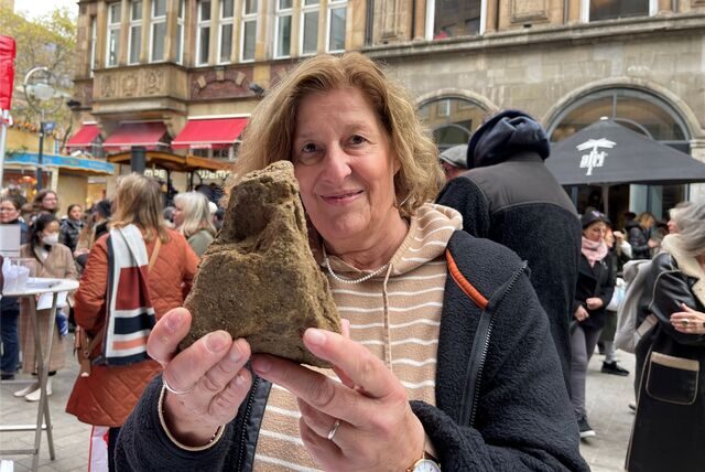 Martina Furlan zeigt einen der Steine der mittelalterlichen Dortmunder Stadtmauer, die am Sonntag auf dem Alten Markt herausgegeben worden sind.