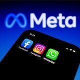 Die Apps von Facebook, Instagram und WhatsApp sind auf einem Smartphone vor dem Logo von Meta Platforms zu sehen.