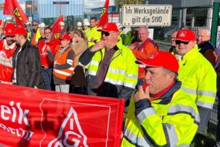 Die Beschäftigten der VDM Metals streiken vor ihrem Werksgebäude.
