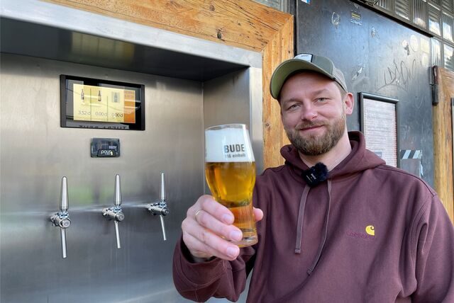 Nico Nahalewicz präsentiert ein frischgezapftes Bier. Seine Gäste können es sich an der Außenwand seiner Gastronomie jetzt selbst zapfen.
