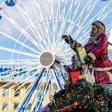 Ein Nikolaus mit Geschenken sitzt beim Weihnachtsmarkt in Duisburg auf dem Dach einer Glühweinhütte.