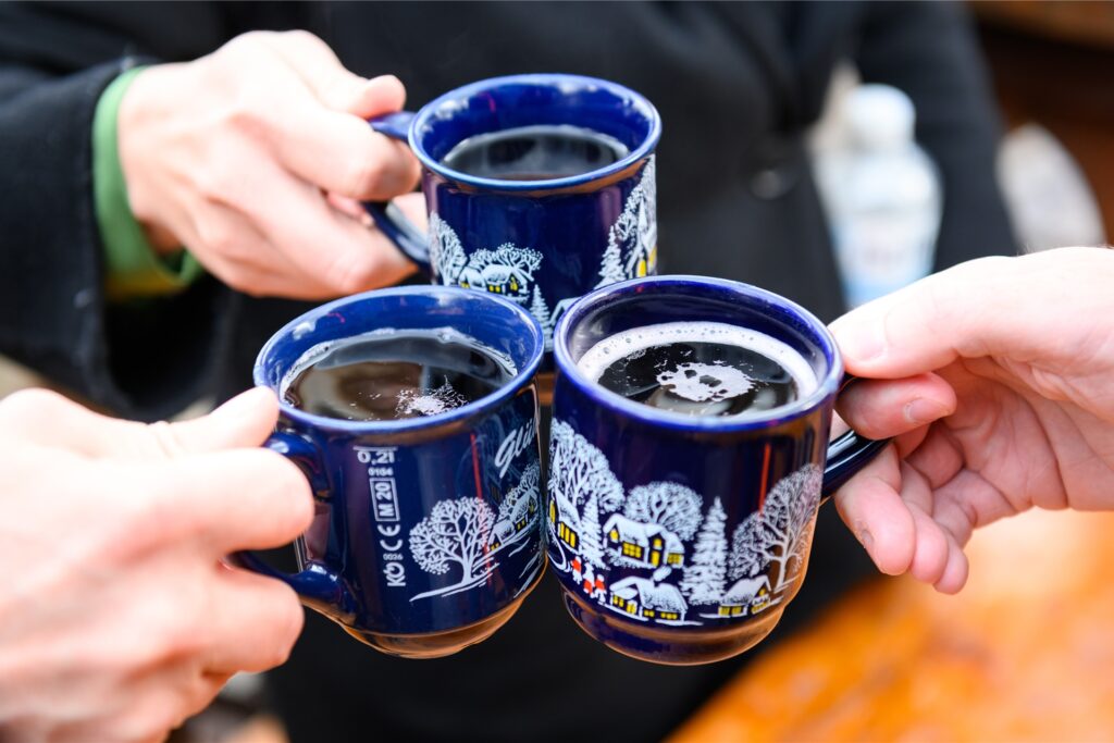 Drei Personen stoßen auf einem Weihnachtsmarkt mit Glühwein an. Drei Personen stoßen auf einem Weihnachtsmarkt mit Glühwein an.