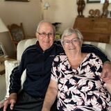 Heinz und Elsbeth Slominski sitzen in ihrem Wohnzimmer auf dem Sofa. Er hat den Arm um sie gelegt. Seit 70 Jahren sind sie glücklich verheiratet.