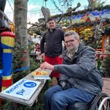 Christian Baran isst auf dem Weihnachtsmarkt eine Pommes an einem Tisch für Rollstuhlfahrer.