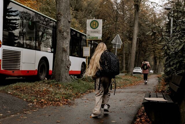 Ein blondes Mädchen läuft zur Bushaltestelle in Haltern. Der Bus fährt ohne sie ab.