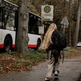 Ein blondes Mädchen läuft zur Bushaltestelle in Haltern. Der Bus fährt ohne sie ab.