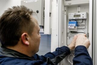 Ein Elektriker montiert einen digitalen Stromzähler mit einem Smart-Meter-Gateway zur Datenübertragung.