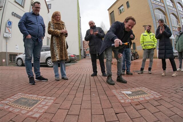 Schauspieler Fabian Busch tauft seine Platte mit Sekt. Das freut (v.l.) Cineworld-Chef Lutz Nennmann, Schauspielerin Nina Petri, Künstler Andrzej Irzykowski, einen Mitarbeiter der Märkischen Tiefbau, Sonja Hofmann und Paula Döring (Kinofest).