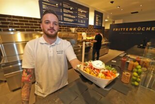 Bei der Frittenküche in der Neue Mühle in Unna kommt in der Regel mehr auf die Pommes als bloß Mayo und Ketchup. Betriebsleiter Jannik Moritz zeigt eine der Kreationen, die sich alle Unnaer ab sofort schmecken lassen können.