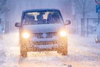 Ein Auto fährt durch Schneetreiben.