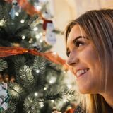 Eine Frau freut sich über beim Anblick eines Weihnachtsbaumes.