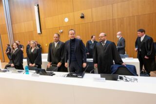 Der frühere Wirecard-Vorstandschef Markus Braun (M) steht zum Prozessauftakt an der Anklagebank zwischen seinen Anwälten Alfred Dierlamm (links neben Braun) und Nico Werning (rechts neben Braun).