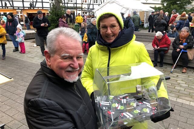 Wolfgang Hüttner und Mechthild Wittmann vom Fröndenberger Werbering tragen die Lostrommel auf die Bühne des Christkindelmarktes. Zur ersten Tomboloziehung gegen 14.30 Uhr füllte sich der Marktplatz merklich.