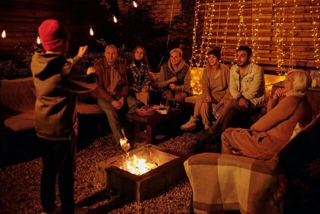 gruppe von menschen beim scharade spielen am lagerfeuer