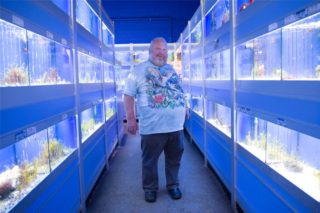 Norbert Zajac steht im Gang zwischen Aquarien. Norbert Zajac steht im Gang zwischen Aquarien.