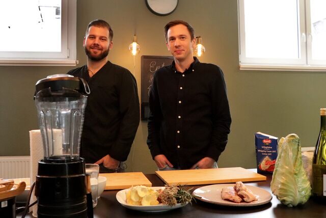 Sternekoch Philip Schneider und Moderator Bastian Pietsch in der Show-Küche. Im Vordergrund liegen einige Zutaten auf dem Tisch.