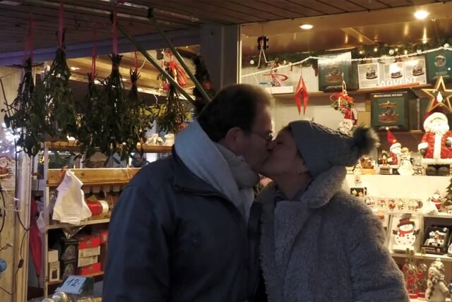 Ein Paar küsst sich unter einem Mistelzweig auf dem Dortmunder Weihnachtsmarkt.