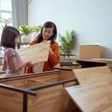 Mutter und Tochter bauen ein Holzregal auf.