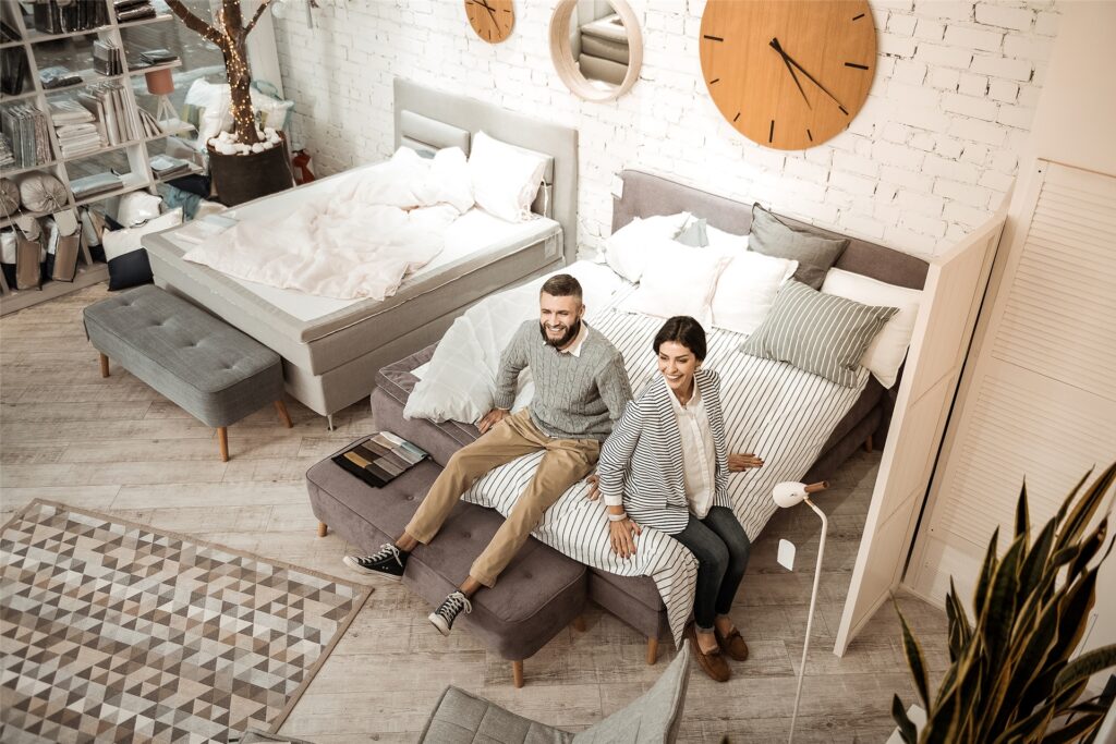 Glückliches Paar sitzt auf einem Bett im Möbelhaus. Glückliches Paar sitzt auf einem Bett im Möbelhaus.