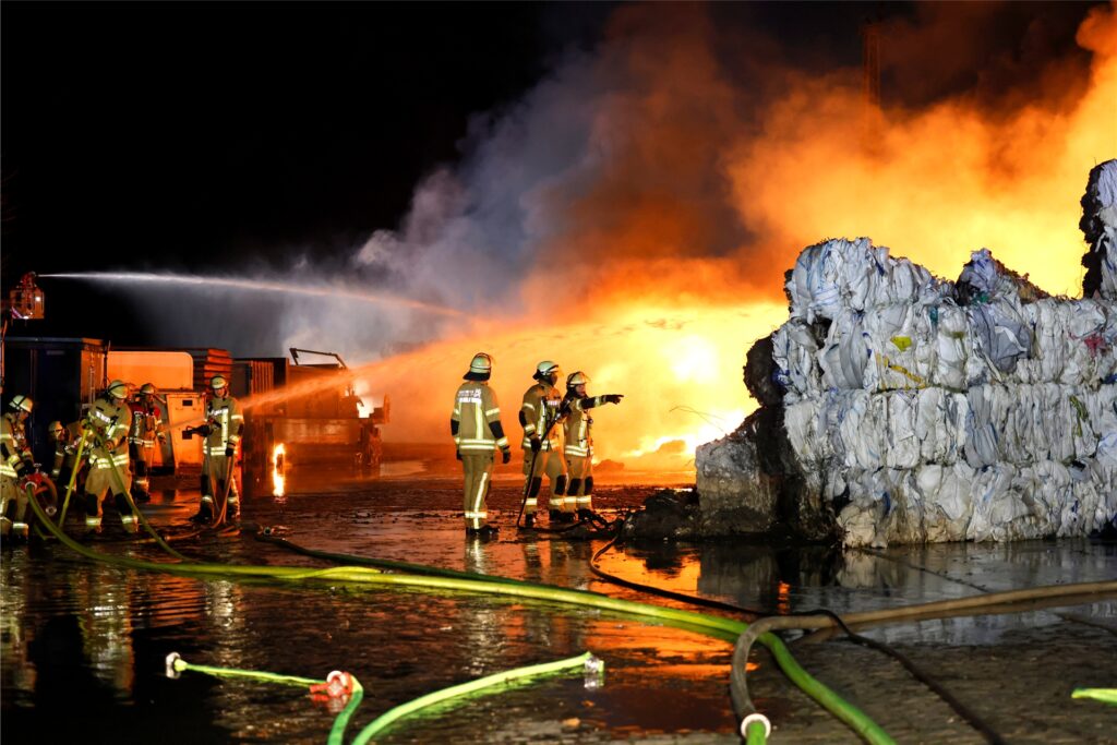 Feuerwehrleute im Einsatz, im Vordergrund stehen verbrannte Papierrollen. Feuerwehrleute im Einsatz, im Vordergrund stehen verbrannte Papierrollen.