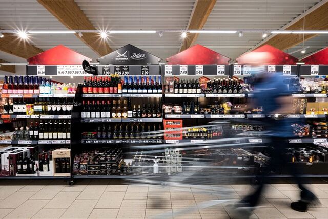 Einkaufsgang im Supermarkt. Mann geht mit Wagen entlang.