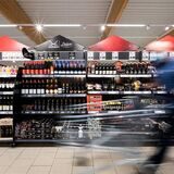 Einkaufsgang im Supermarkt. Mann geht mit Wagen entlang.