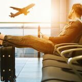 Ein Mann sitzt im Wartebereich an einem Flughafen