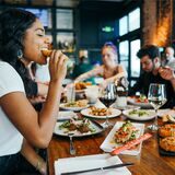 Mehrere Menschen sitzen an einem Tisch und essen.