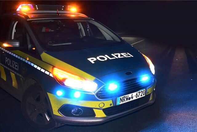 Ein Fahrzeug der Polizei NRW parkt Nachts mit Blaulicht.