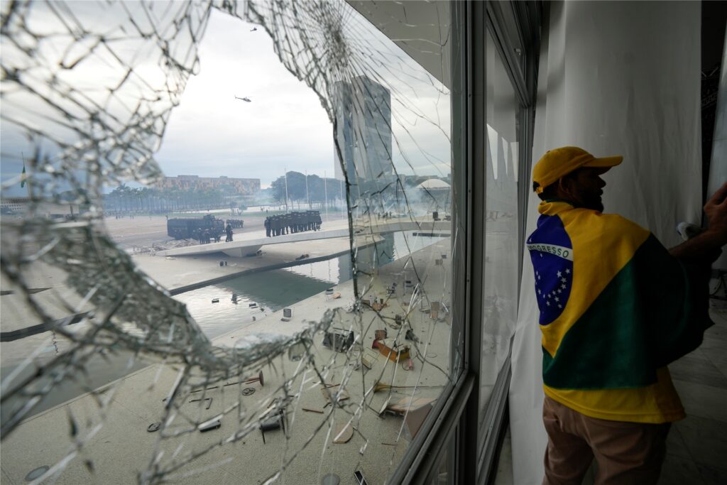 Polizisten sind durch ein zerbrochenes Fenster zu sehen. Polizisten sind durch ein zerbrochenes Fenster zu sehen.