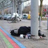 Ein wohnungsloser Mensch liegt unter einem Glasdach vor dem Dortmunder Hauptbahnhof.
