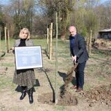 Bürgermeister Dirk Wigant pflanzte 2022 den elften Baum an der Gedenkstätte „10+1“, während  Ksenija Sakelsek, Vorsitzende des Integrationsrats, die Gedenktafel zeigte.