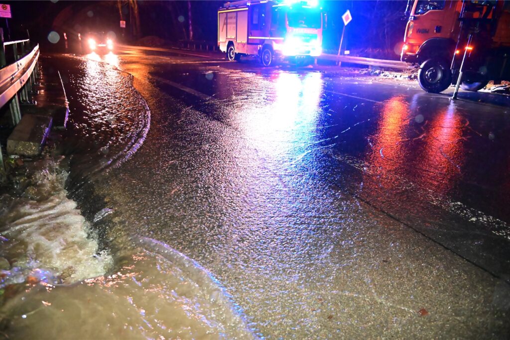 Einsatzkräfte der Feuerwehr sind bei einer durch Dauerregen überfluteten Straße durch Überschwemmung der Volme im Einsatz.