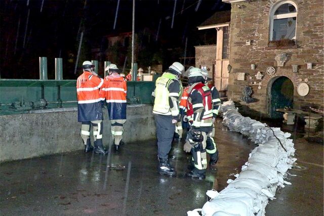 Einsatzkräfte der Feuerwehr bauen einen Damm aus Sandsäcken zum Schutz vor dem Hochwasser.