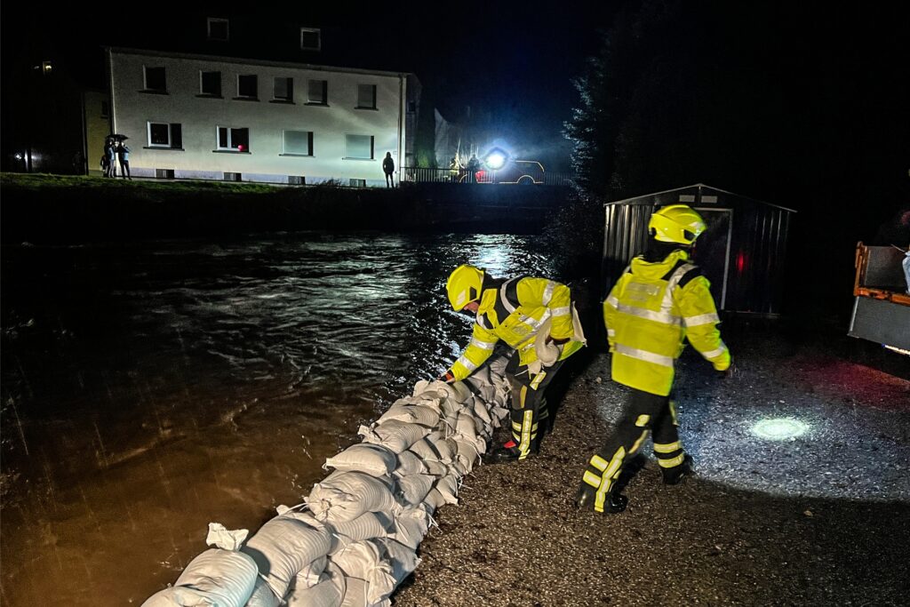 Einsatzkräfte der Feuerwehr bauen einen Damm aus Sandsäcken zum Schutz vor dem Hochwasser. Einsatzkräfte der Feuerwehr bauen einen Damm aus Sandsäcken zum Schutz vor dem Hochwasser.