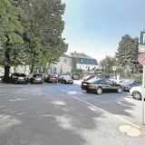 Auf dem Parkplatz an der Schulstraße stehen im Jahr 2018 Autos, teils unter Baumkronen
