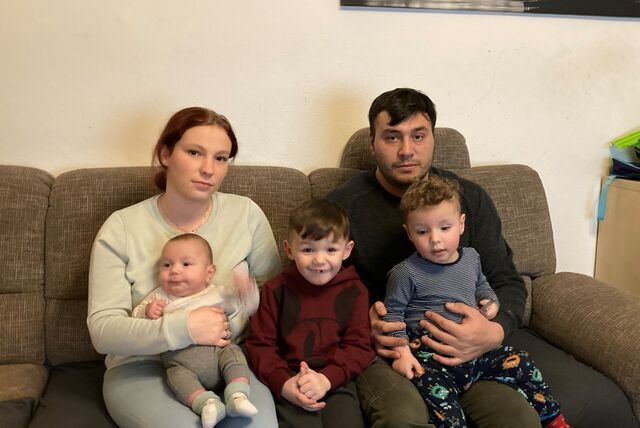 Eine Mutter und ein Vater sitzen mit ihren drei kleinen Söhnen auf einer Couch in ihrer Wohnung in Recklinghausen im Stadtteil Grullbad.