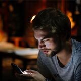 Ein junger Mann hält ein Smartphone in der Hand.