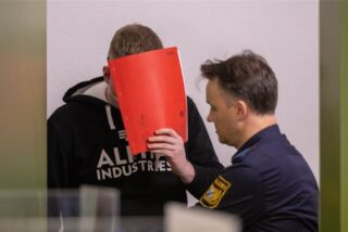 Der angeklagte Krankenpfleger aus Dorsten wird zum Prozess-Auftakt von Justizbeamten in den Gerichtssaal geführt.