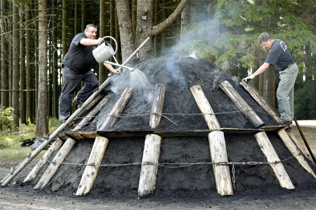 Zwei Brauchtumsköhler in der Hotzenwaldgemeinde Dachsberg (Kreis Waldshut) bearbeiten einen qualmenden Kohlenmeiler. Zwei Brauchtumsköhler in der Hotzenwaldgemeinde Dachsberg (Kreis Waldshut) bearbeiten einen qualmenden Kohlenmeiler.
